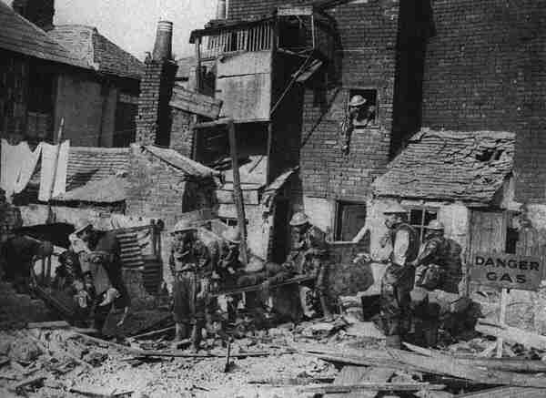 Вынос погибших от иприта из домов одного городов во Фландрии. Снимок,  судя по противоипритной одежде солдат, относится к лету 1918 г .  Серьезных разрушений домов нет, однако погибших много, и действие иприта  продолжается. 