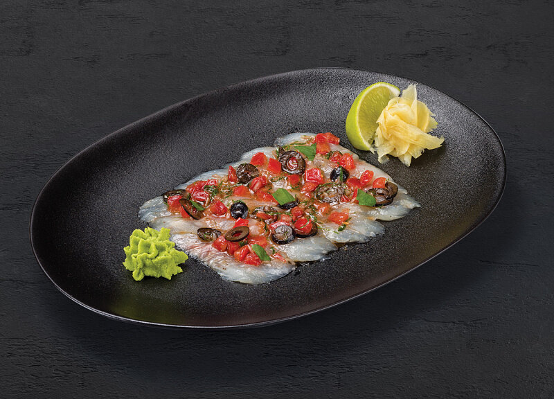 Севиче из сибаса: Нежнейший сибас с томатами и оливками под специями, лимонным соком и оливковым маслом. Подаётся с имбирём и васаби.