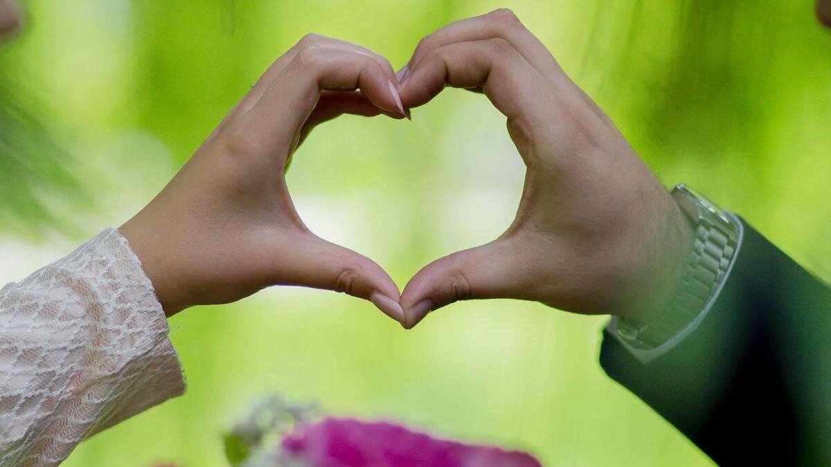    Знак сердечка, сделанный руками супругов:Freepik
