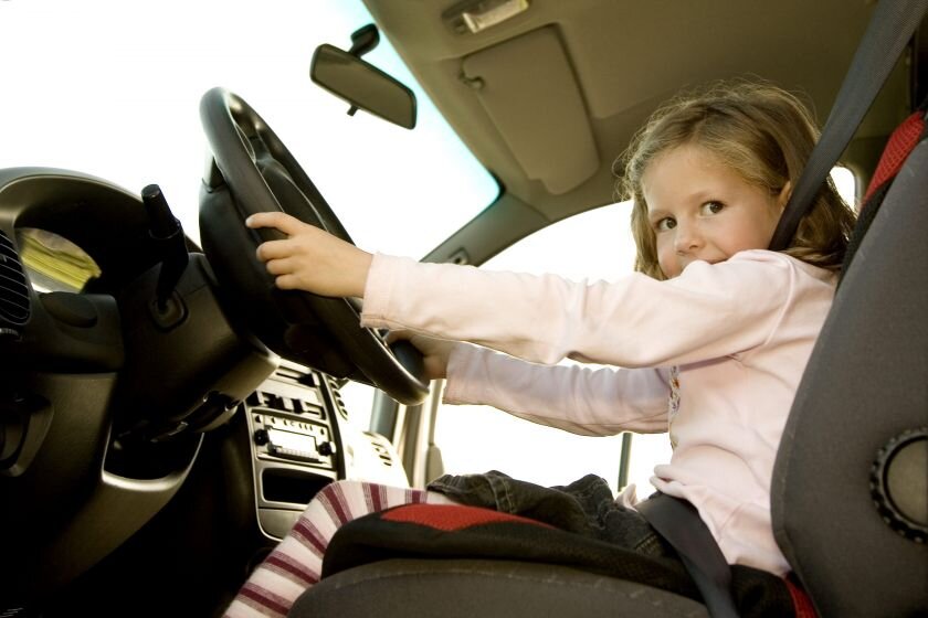 Playing cars. Girl behind. Blonde chubby face behind Steering Wheel.