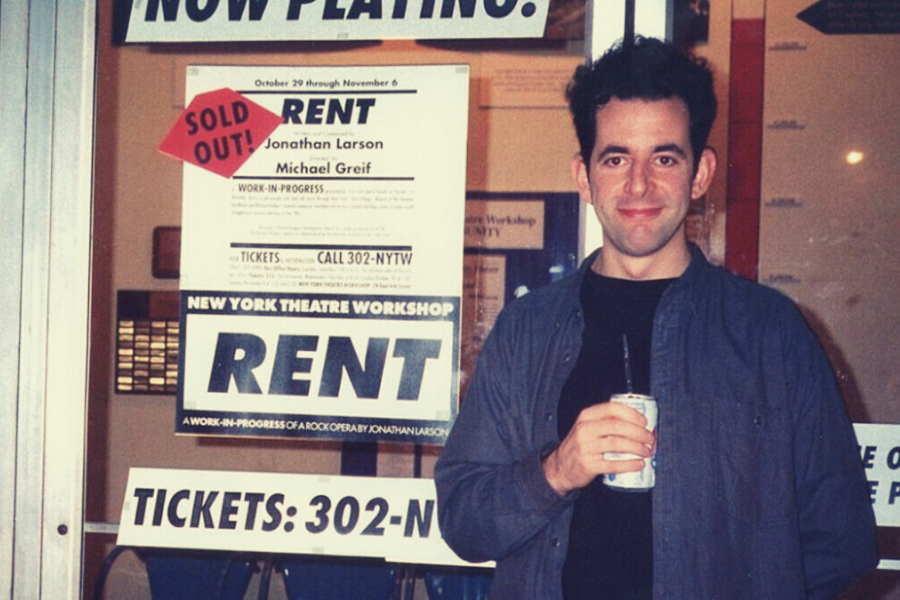 Счастливый Джонатан Ларсон на фоне афиши "Rent" с пометкой о том, что все билеты на предварительный показ проданы.