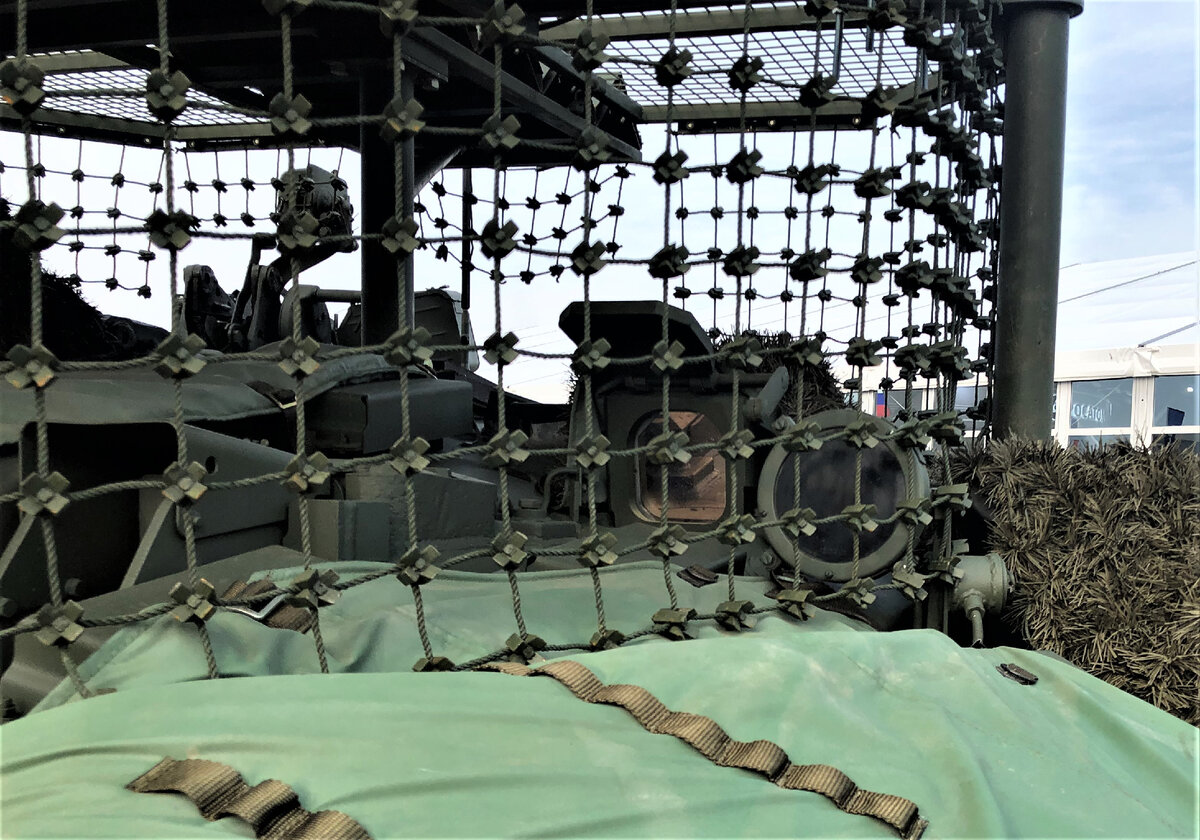 Через защитную сетку виден колпак тепловизионного прицела 1ПН96МТ . Защитная бронешторка в открытом положении, видна часть ручного механизма открытия/закрытия