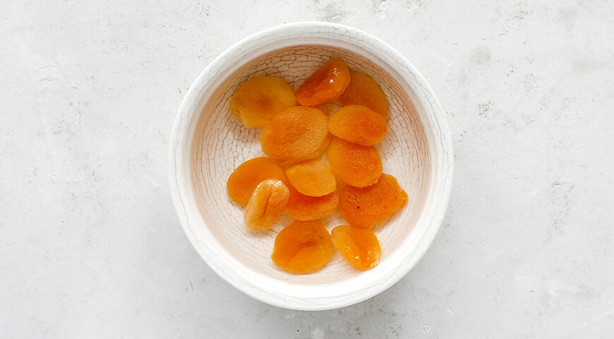 1. Подготовьте ингредиенты пасхи. Курагу тщательно промойте проточной водой и переложите в миску. Залейте кипящей водой так, чтобы она полностью покрыла сухофрукты. Оставьте на 15 минут.