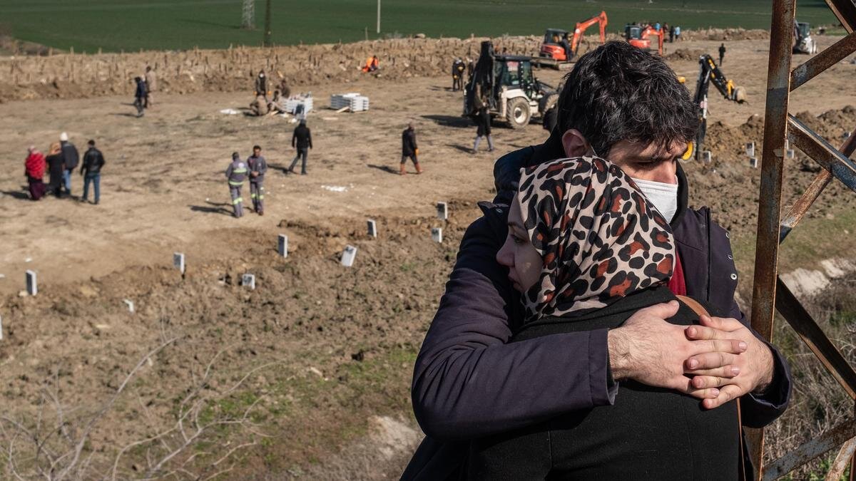    Семья стоит около кладбища в провинции Хатай:Burak Kara / Getty Images