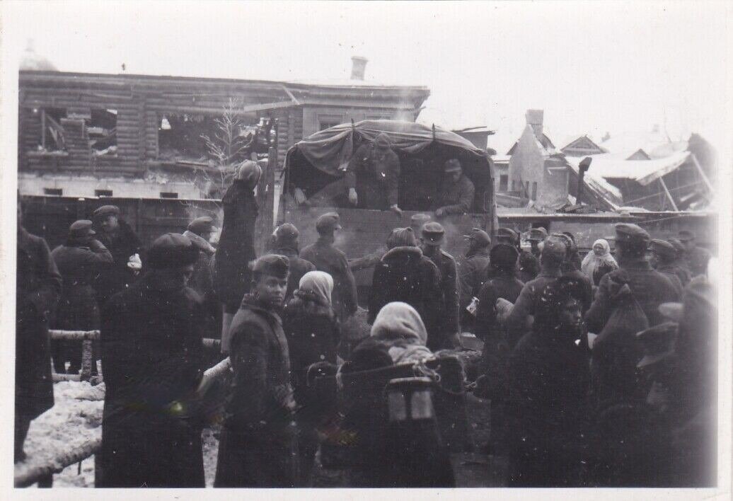 Местное население ждет погрузки в автомашины. Ул. Советская (Великолукская). Дома уже сильно разрушены. 19.02.1944.