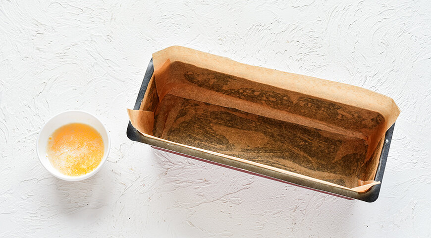 1. Для приготовления недорогого влажного шоколадного пирога предварительно застелите бумагой для выпечки прямоугольную форму размером примерно 20х30 см. Разогрейте духовку до 180С. Сливочное масло растопите на плите или в микроволновой печи.