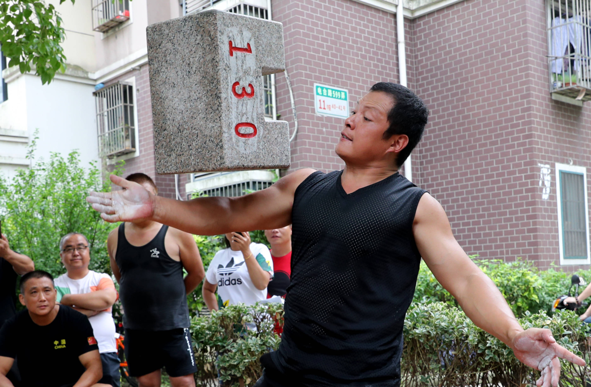  Чжан Чжимин, энтузиаст «каменных замкòв», выполняет упражнение со снарядом весом в 130 цзинь.
