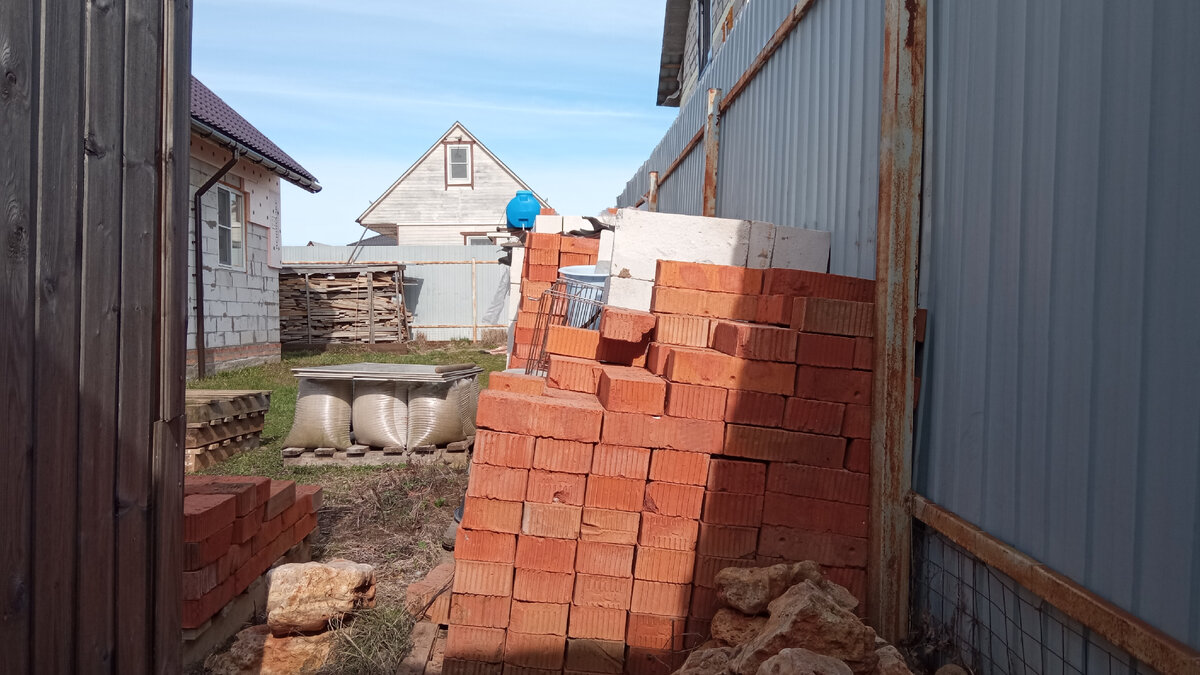 Кирпичи лежат на заборе.