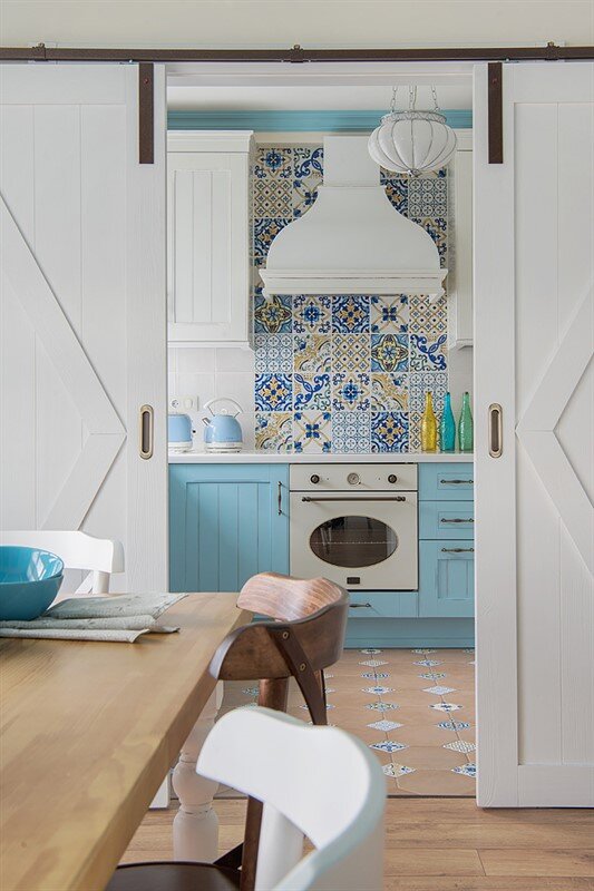Яркая мозаичная плитка над варочной панелью добавила средиземноморской экспрессии спокойным тонам интерьера.