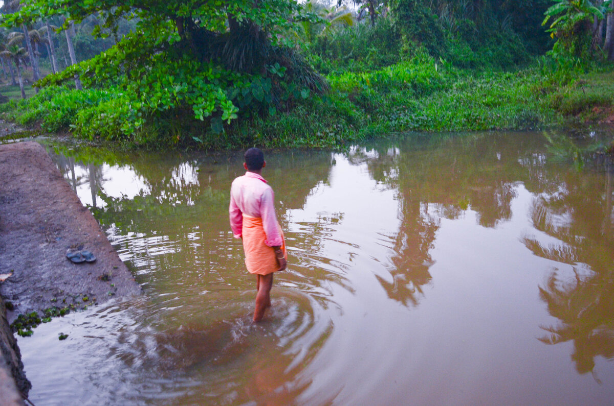 Индус гуляет в канаве, в которую предположительно по запаху сливают отходы. 