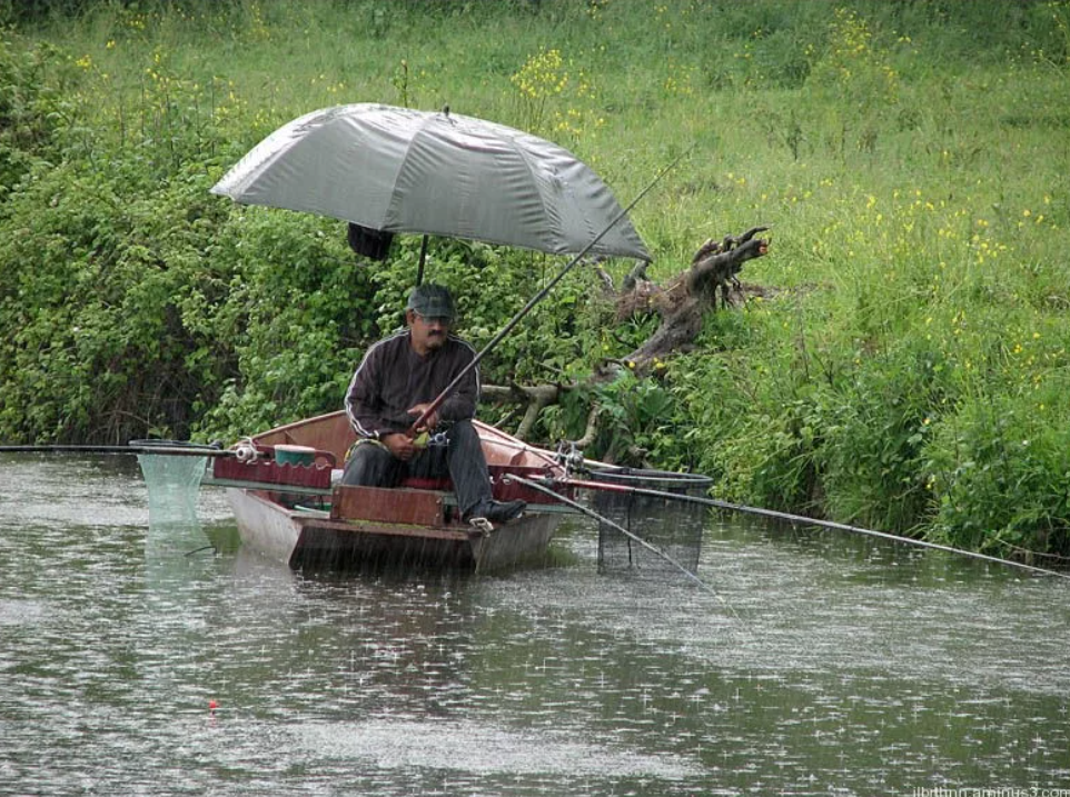 Ловить погоду. Рыбак под дождем. Рыбалка в ливень. Рыбак в лодке под дождём. Рыбак в дождь.