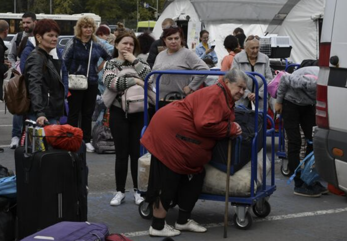 Refugees from war hit eastern Ukraine stand in line waiting for departure in a refugee centre in Zaporizhzhia, Ukraine, Thursday, Sept. 15, 2022. (AP Photo/Andriy Andriyenko)