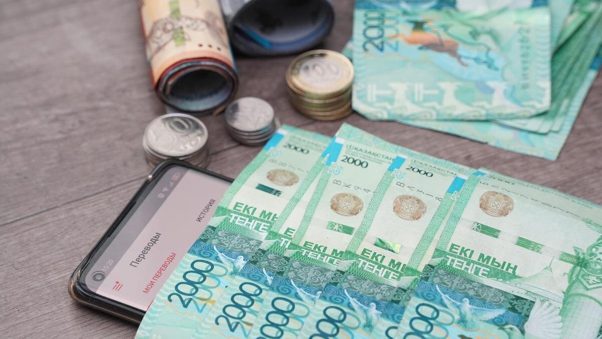    Купюры тенге лежат на телефоне:NUR.KZ/Владимир Третьяков