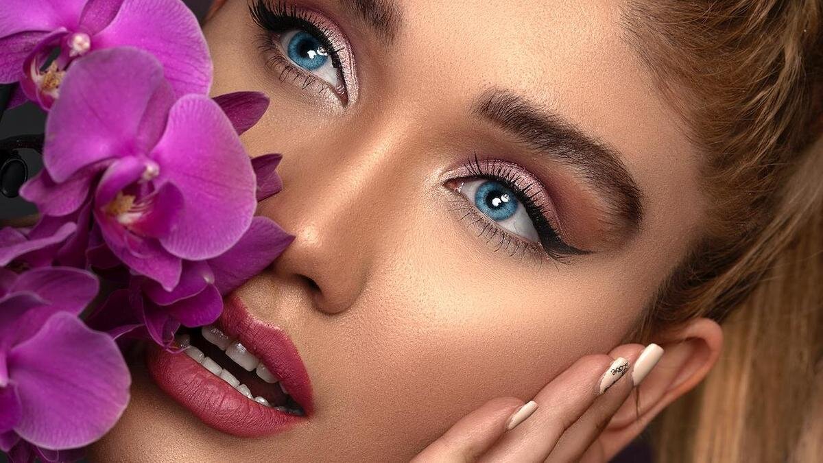    Красивая девушка с черными стрелками держит цветы возле лица:Pexels