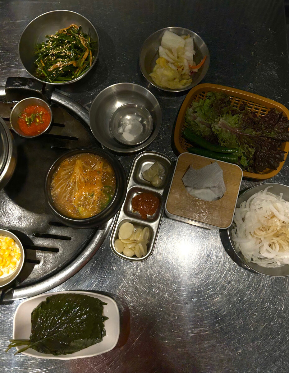 Панчаны: маринованные листы, кукурузы в молоке, имбирь, чеснок, маринованный лук, капустный салат, просто листья салата, соусы. За кадром еще кимчи. 