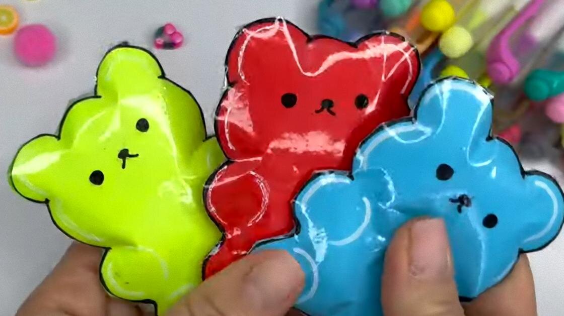    В руках держат трех разноцветных мишек-сквишей из бумаги:YouTube/Лум Планет