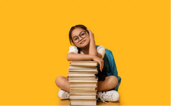     Источник фото: https://stock.adobe.com/ru/images/korean-schoolgirl-sitting-at-books-stack-in-studio-yellow-background/376452673