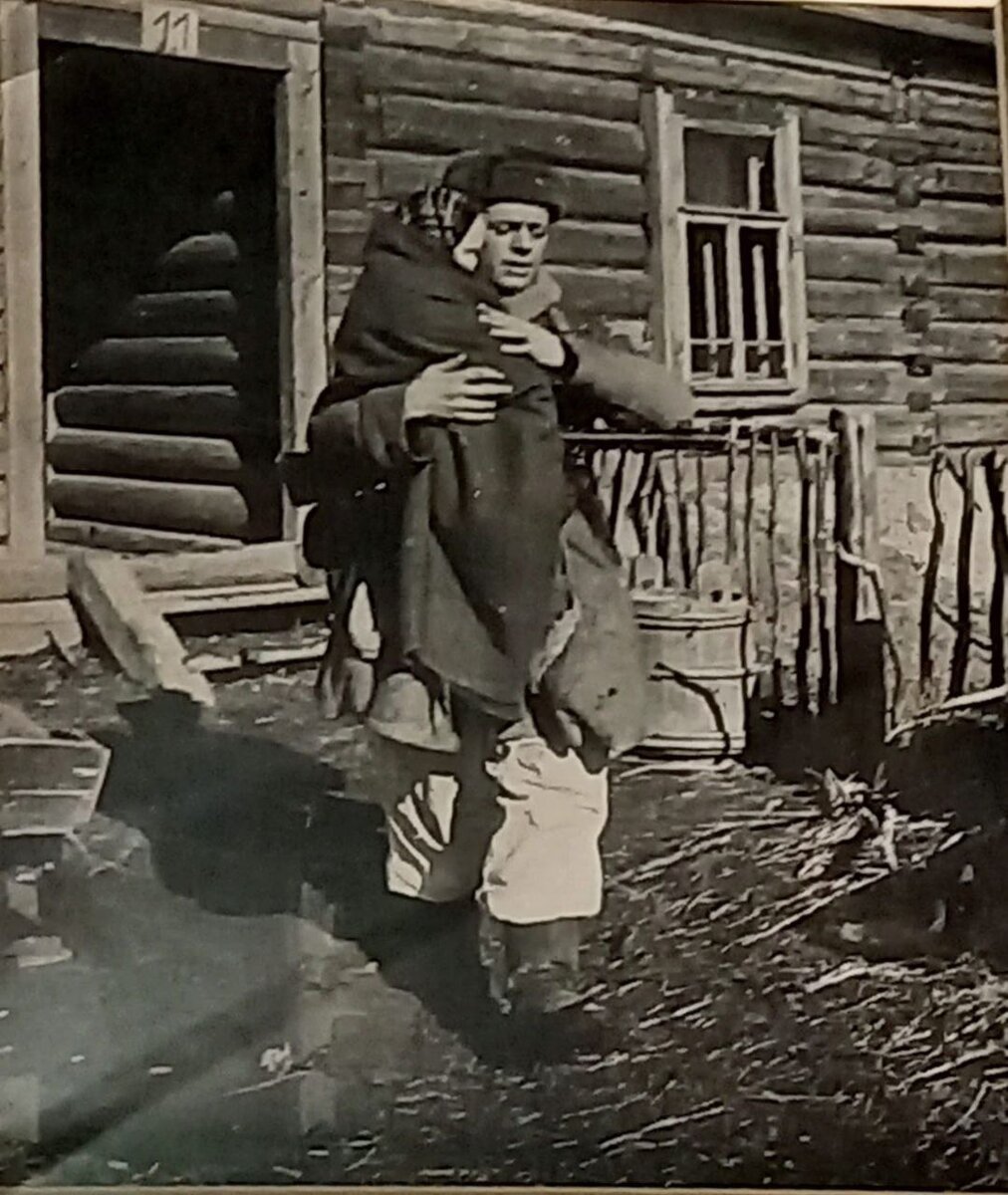 Старший сержант В.А. Моисеев выносит из дома девочку