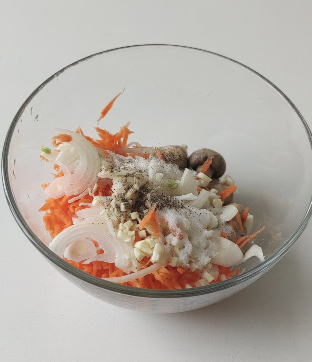 Пока шампиньоны варятся трем на крупной терке морковь (100 г), нарезаем лук тонкими полукольцами (50 г) и рубим мелко чеснок 3-4 зубчика. Добавляем по чайной ложке соли и сахара и треть чайной ложки перца