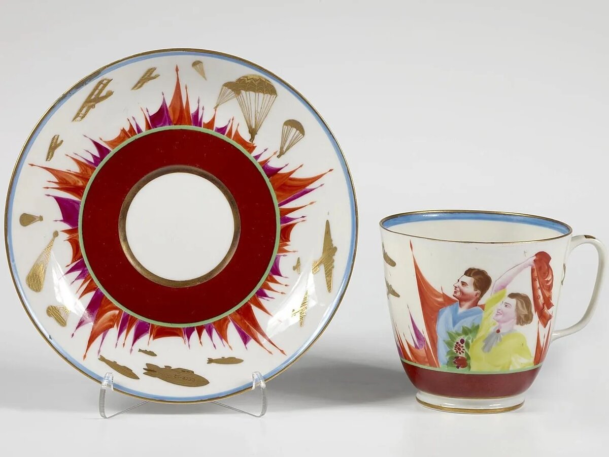 МИХАИЛ МОХ. ЧАШКА С БЛЮДЦЕМ «ДЕНЬ АВИАЦИИ». НАДГЛАЗУРНАЯ ПОЛИХРОМНАЯ РОСПИСЬ, ПОЗОЛОТА, ЦИРОВКА. 1936. ГОСУДАРСТВЕННЫЙ ЭРМИТАЖ, САНКТ-ПЕТЕРБУРГ