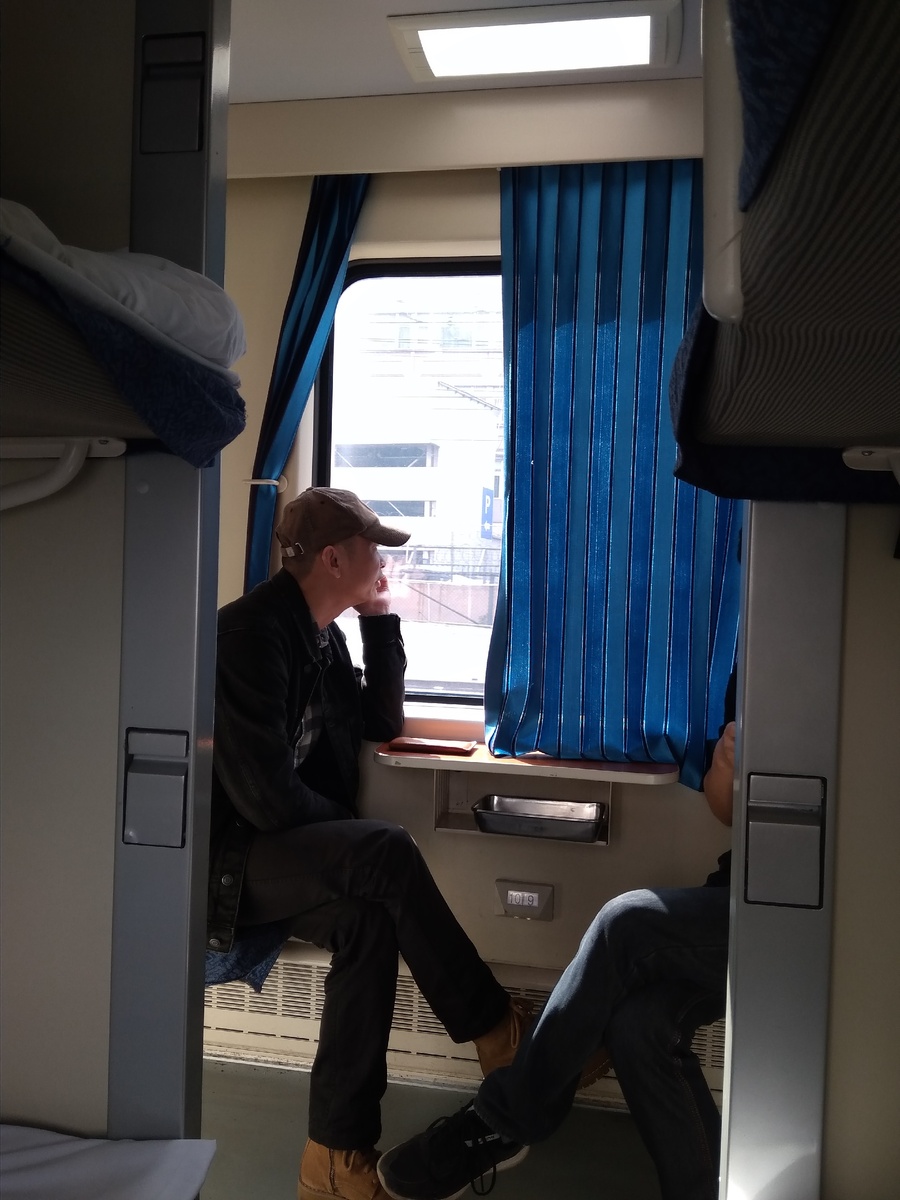 в китайском поезде, фотограф и студент о чем то разговаривают