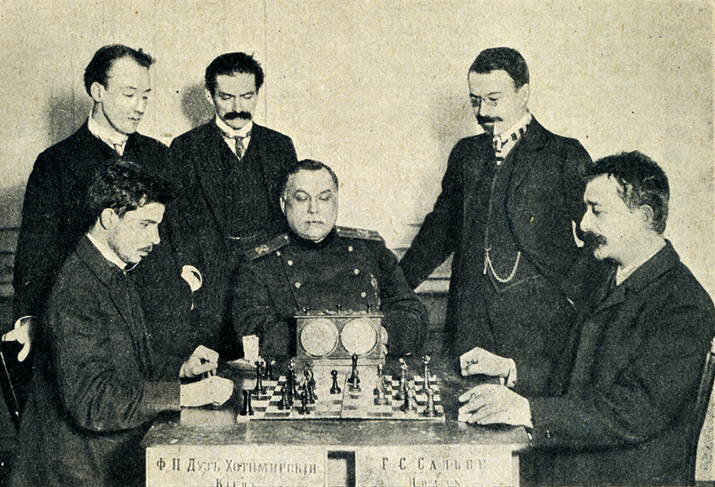 Петербург, 1909, турнир памяти Михаила Чигорина. За партией Георг Генрих Сальве – Фёдор Дуз-Хотимирский (на фото слева) наблюдают (слева направо) члены турнирного комитета В.Чудовский и Ю.Сосницкий, председатель Лодзинского общества любителей шахматной игры К.Манакин и мастер А.Левин. Эту партию Дуз проиграл, но зато – единственный! – выиграл у Эмануила Ласкера и Акибу Рубинштейна! Фото из турнирного сборника