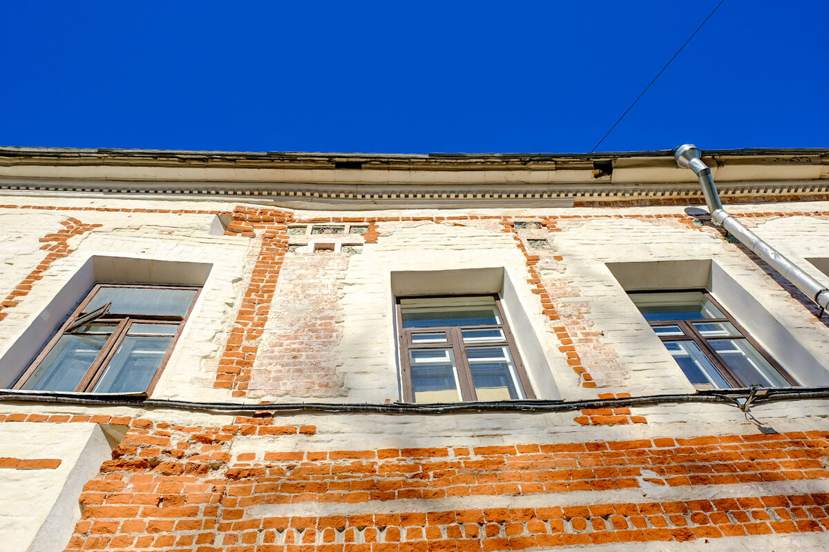 Фасад дома Ярошенко, Чистый кирпич показывает, где находился утраченный декор. Сверху видны три старинных изразца.