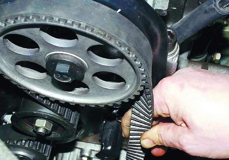  Ремень и ролик ГРМ ВАЗ 2114 8 клапанов  Итак, вы воочию столкнулись с данной проблемой, а деталь пришла в непотребное состояние или вовсе порвалась. Для того, чтобы замена прошла успешно, совершенно не обязательно обращаться в автосервис, поскольку, дело это хоть и трудоемкое, но вполне осуществимое и своими руками. Замена ремня ГРМ в ВАЗ модели 2114, должна производиться следуя инструкции, приведенной ниже.  1. Автомобиль устанавливаем на ровном месте, включаем передачу и ставим на ручник.  2. С помощью ключа на 10 откручиваем болты крепления кожуха привода ГРМ.   3. Ослабляем натяжитель ремня генератора с помощью ключа на 13. Снимаем ремень.    4. Сверяем метки на шестерне распредвала и выступе на задней крышке кожуха ремня.   5. Если они не совпадают, нужно провернуть коленвал до совпадения. Это можно сделать путем вращения переднего колеса, предварительно поддомкратить его, или же провернуть коленвал ключом на 17, за болт крепления шкива коленчатого вала (передача должна быть включена).  6. За 4-м цилиндром на картере сцепления есть резиновая заглушка. Открываем ее, поддев отверткой. Под ней видно венец маховика, на котором также есть метка. Она должна совпадать с треугольным пропилом, находящимся на картере слева от маховика.  7. Если они не совпадают, нужно отпустить крепление натяжного ролика, повернуть его влево, ослабив таким образом ремень, и снять его с шестерни распределительного вала.   8. С помощью ключа на 17 проворачиваем коленвал, как было описано выше, пока все метки не совпадут.  9. Обездвиживаем маховик, застопорив его отверткой в отверстии, где находилась заглушка.   10. С помощью ключа на 17 выкручиваем болт, крепящий шкив генератора.   11. За ним находится шкив коленвала, на который надевается ремень, подлежащий замене.  12. Снимаем старый и надеваем новый ремень ГРМ, начиная с шестерни коленчатого вала.    13. Прикручиваем шкив генератора, надев на него ремень. Натягиваем его.  14. Старый натяжной ролик демонтируем, ставим новый, смазав его с обеих сторон маслом.  15. Проводим натяжение ремня ГРМ, проворачивая ролик натяжителя вправо (если нет специального ключа, можно вставить в отверстия два подходящих штыря и зафиксировать отверткой или другим похожим предметом). Натяжение должно составлять 1,5-2 кгс. Если у вас нет инструмента для того чтобы замерить величину натяжения, делаем это старым проверенным способом. Оптимальным считается натяжение, когда одну плоскость ремня можно развернуть горизонтально на 90 градусов, взявшись пальцами посредине между шестернями коленвала и распредвала.   16. В этом положении затягиваем болт крепления натяжного ролика.    17. Вынимаем отвертку из отверстия картера сцепления, ставим на место заглушку. Защитный кожух ремня ГРМ не устанавливаем, пока не проверим работу всего привода.  Заключение Завершив ремонтные работы, запустите двигатель. Оцените звук работы мотора. Если все сделано правильно, никаких посторонних шумов быть не должно.  При сильном натяжении ремня ГРМ возможен гул ролика натяжителя. В этом случае его крепление нужно ослабить, и провернуть ролик на 10-15 градусов влево, после чего опять надежно зафиксировать.
 