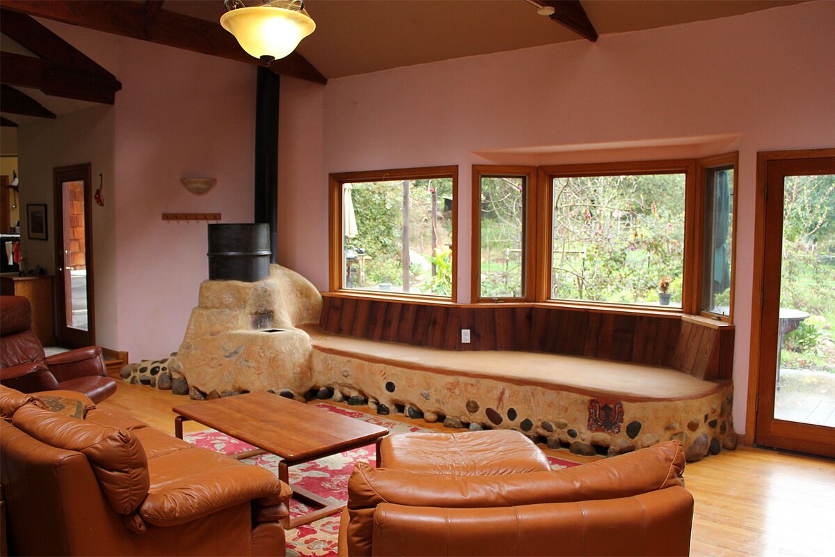 Ракетная печь с массивным теплонакопителем. Основными отличиями от других печей является то, что в ракетных печах труба находится внутри самой печи, поэтому она очень сильно наргевается, что даёт мощную тягу, а дымоход проходит через саманную мебель, нагревая её и сохраняя всё тепло внутри помещения, отдавая его до нескольких суток.