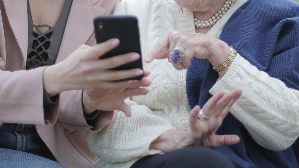    Женщины сидят на лавочке и смотрят в телефон:pexels.com