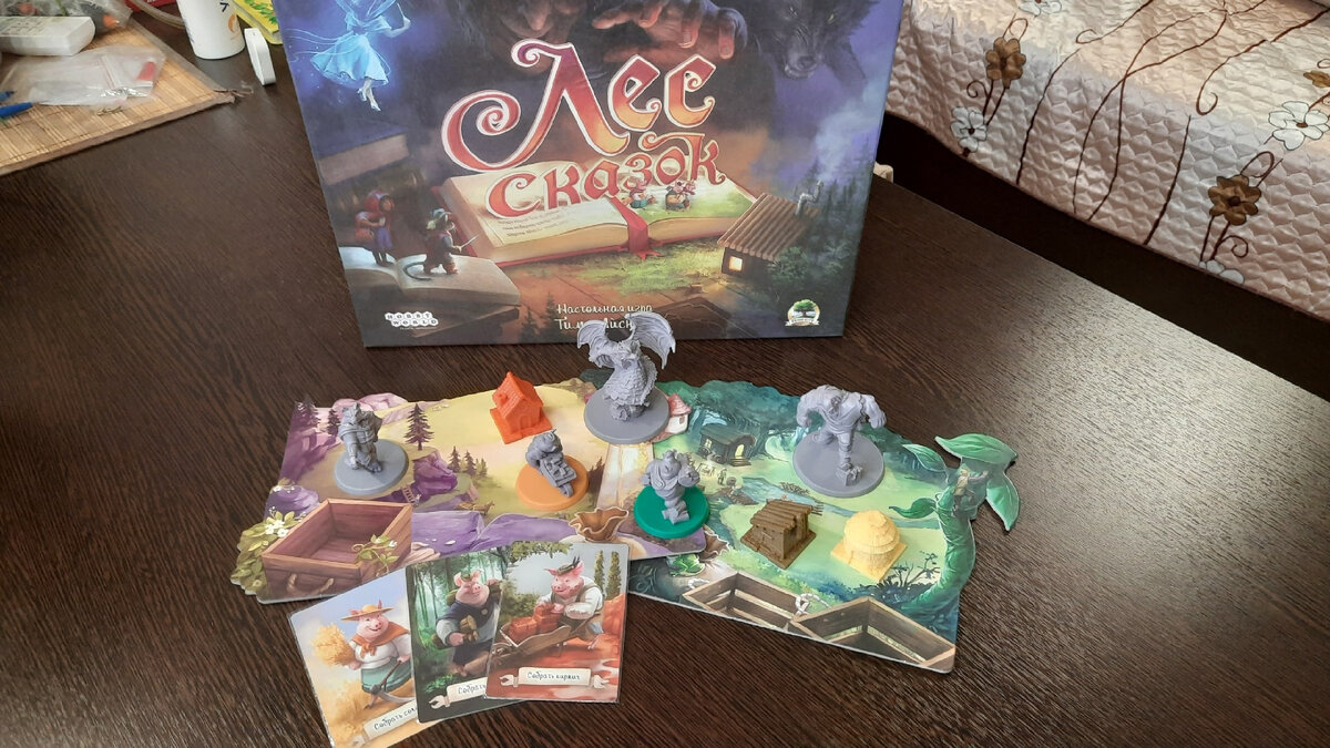 Настольная игра "Лес сказок". На фото пара планшетов, пара фигурок поросят, разные домики, несколько монстров (великан, дракон, волк), карты сбора ресурсов.