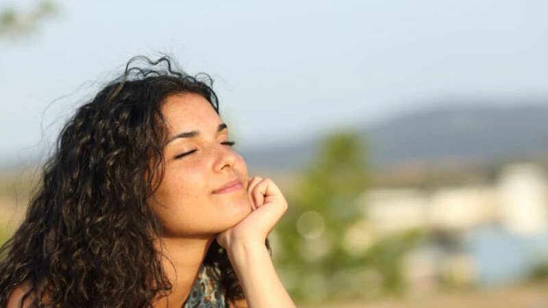 Woman relaxing and enjoying the sun in a warmth park at sunset