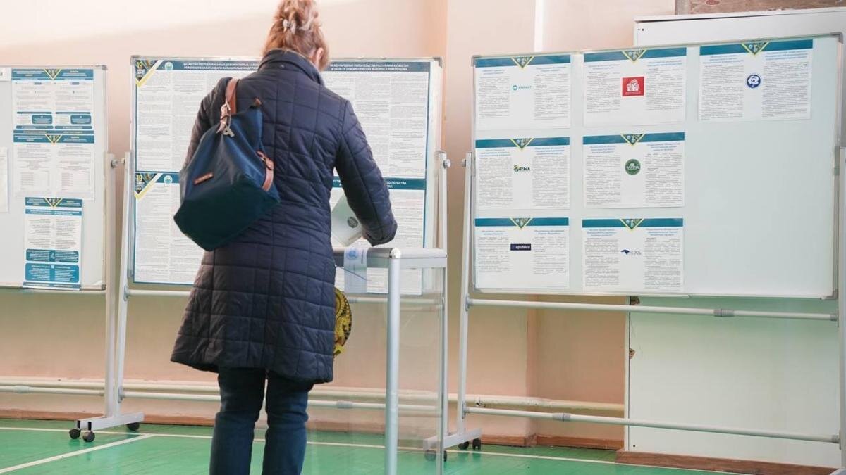   Женщина кидает бюллетень в урну:NUR.KZ / Владимир Третьяков