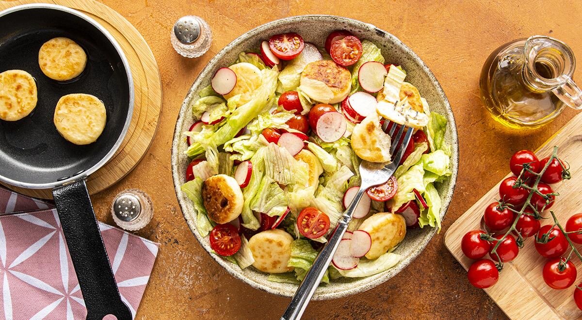 Салат айсберг с мини-сырничками и помидорами черри можно организовать всего за полчаса. Причем самое сложное – выпечь маленькие сырники, но с этим вы точно справитесь, мы уверены. А дальше все просто: нарежьте помидор и редис, порвите салат и сделайте соус. Для заправки вам понадобится оливковое масло, лимонный сок и специи по вкусу.