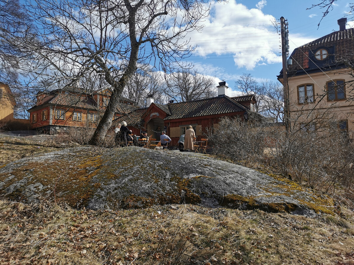 Городской квартал и здание кафе по центру фотографии, на переднем плане - открытая терраса кафе