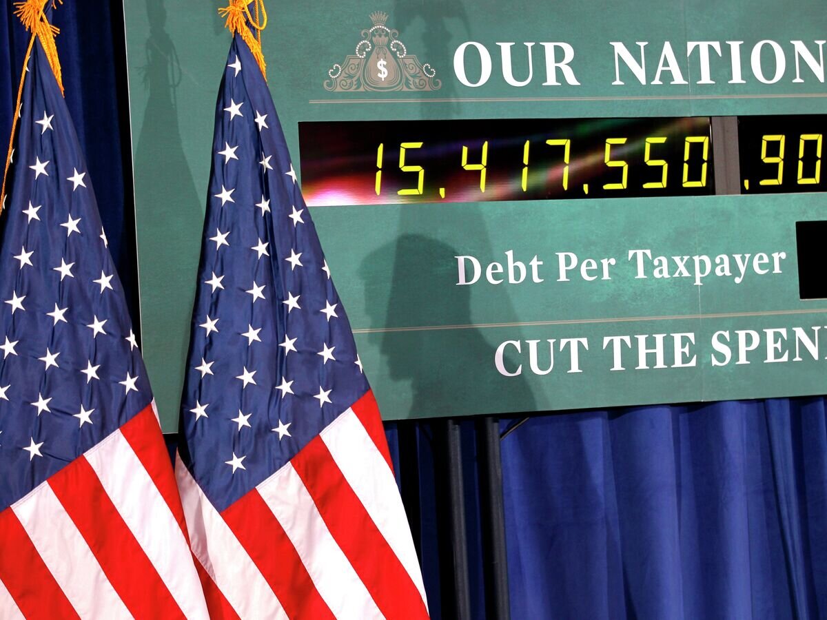    Тень кандидатав президенты США Митта Ромни на фоне часов, показывающих рост госдолга США© AP Photo / Gerald Herbert