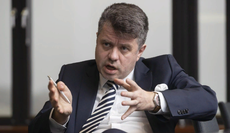 Урмас Рейнсалу показывает как он будет сокращать вдвое потолок цены (фото с сайта delfi.ee) 