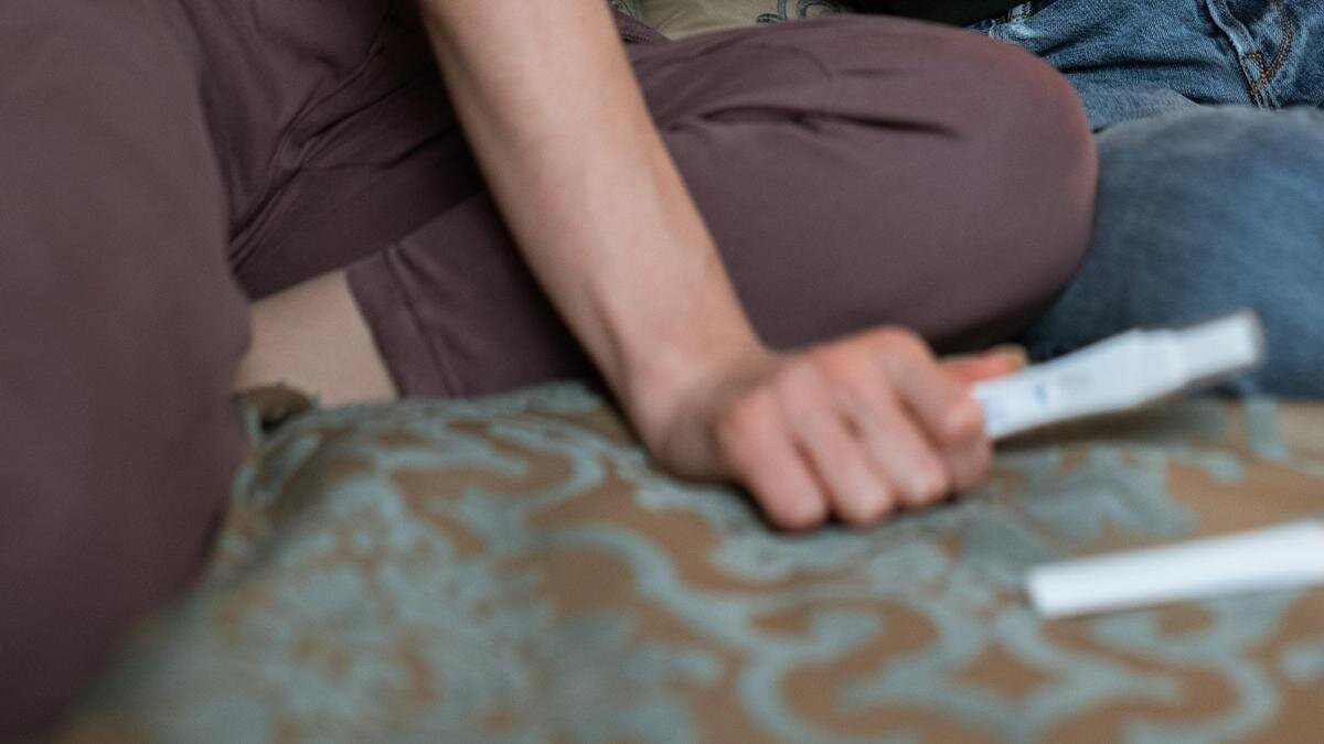    Девушка сидит на кровати и держит тест на беременность:pexels.com