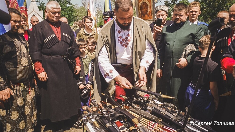 Каждый по очереди подошёл к столу и бережно уложил своё оружие. Ждут освящения.