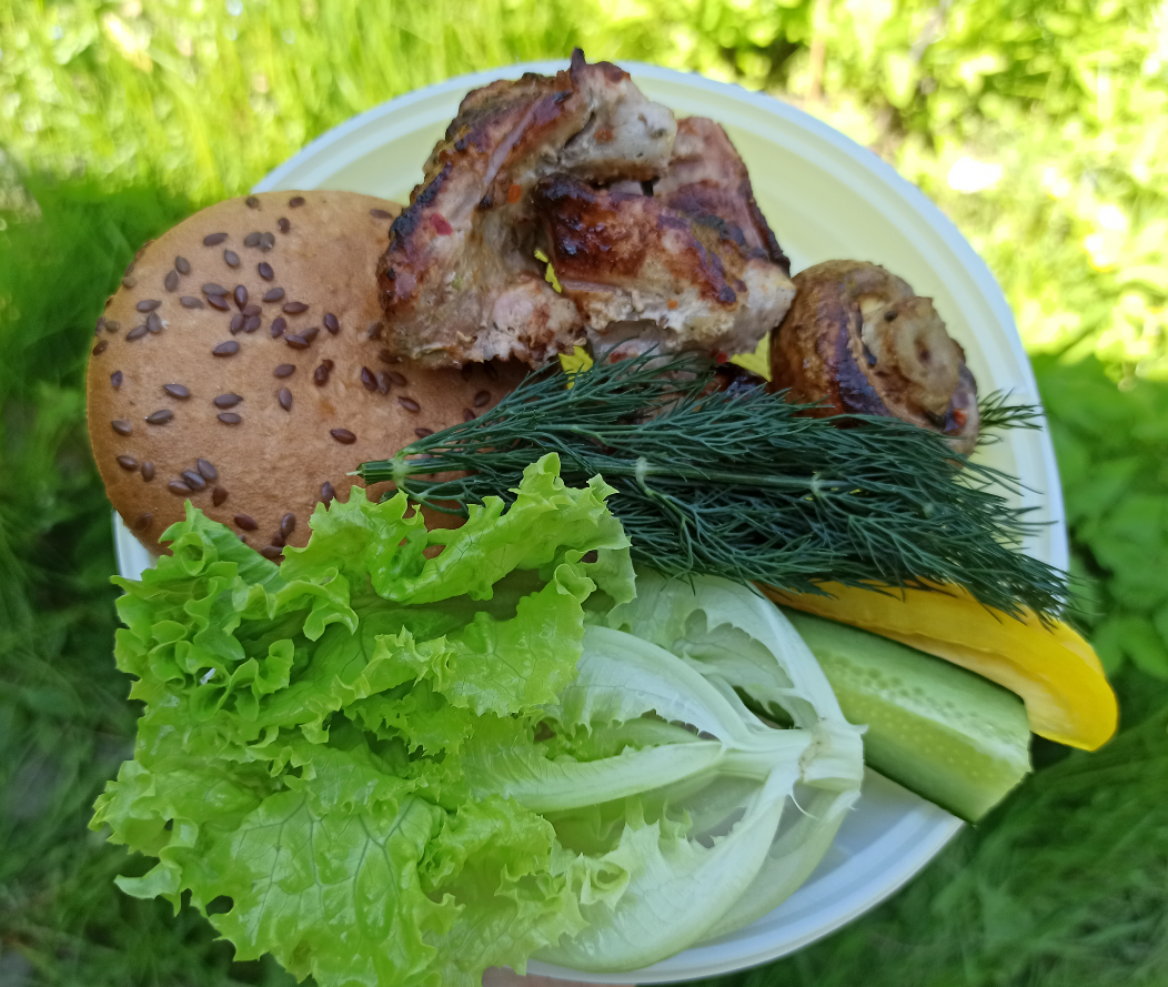 В тарелке: кусочек шашлыка, шампиньон, булочка фкдкод (безглютеновая), огурец, перец, салат, укроп