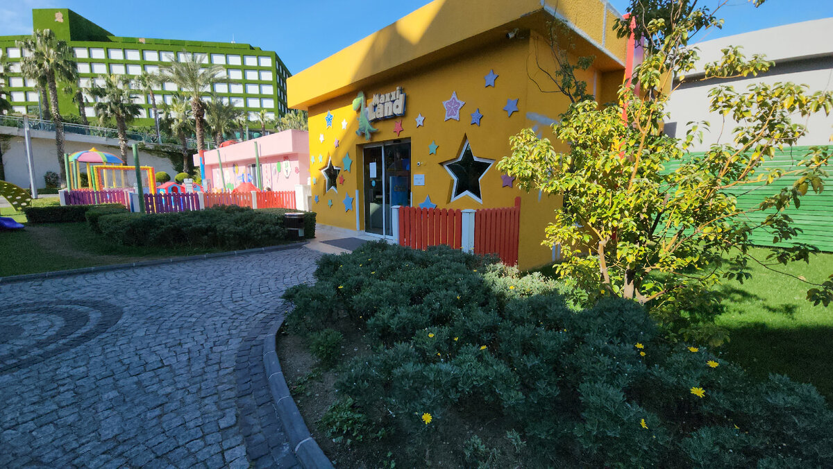 Вход в клуб, слева открытая детская площадка. Вдали отель Адам и Ева.