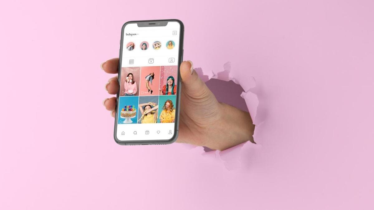    В руке телефон, на котором запущено приложение Instagram:Freepik