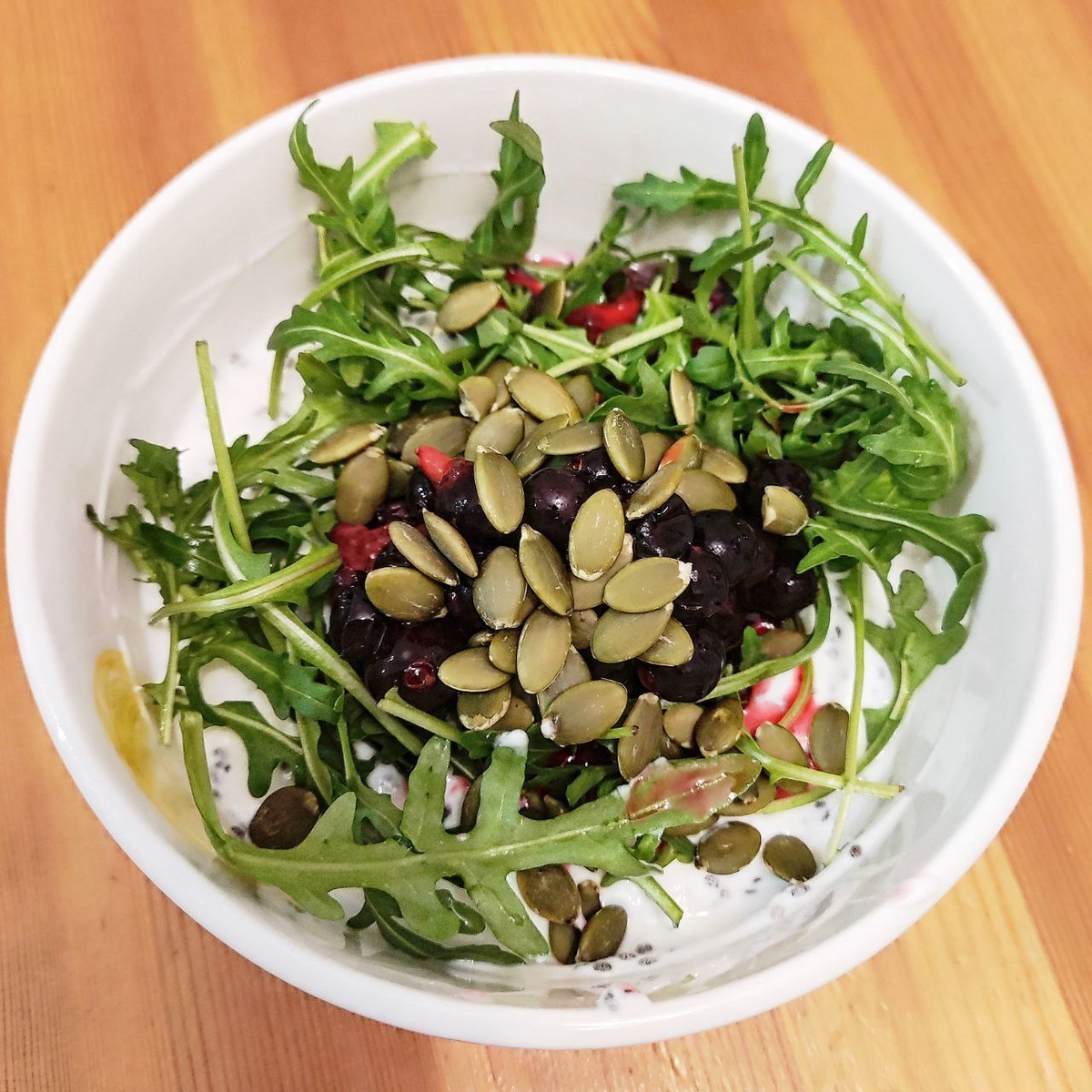 Пример полноценного завтрака: йогурт с семенами чиа, ягодами, тыквенными семечками и рукколой.