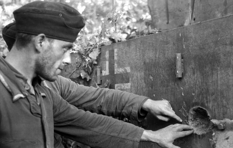 Немецкие солдаты осматривают выбоину от попадания снаряда в бортовую броню танка «Тигр». Фото в свободном доступе.
