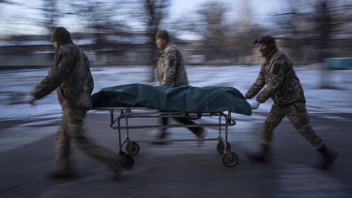    Украинские военнослужащие перевозят носилки с погибшим в Донецкой области© AP Photo / Evgeniy Maloletka