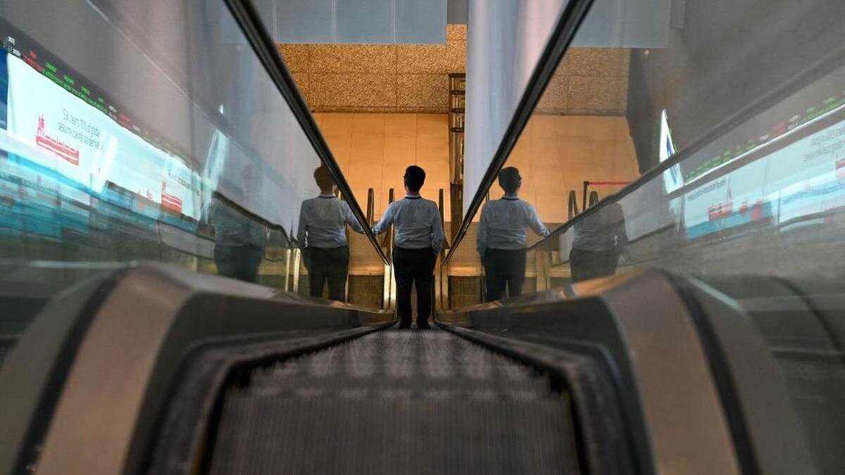    Мужчина спускается вниз на эскалаторе:Roslan Rahman / AFP / Getty Images