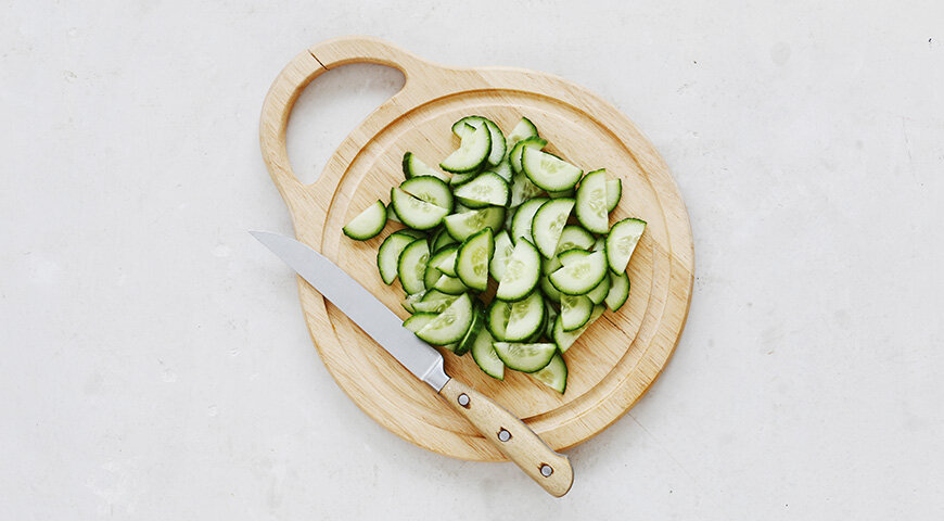 1. Подготовьте все ингредиенты для греческого салата. Свежие огурцы и помидоры вымойте, затем обсушите бумажными полотенцами. Огурцы разрежьте вдоль пополам, затем нарежьте крупными ломтиками.