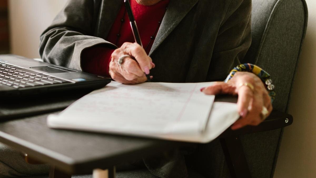    Женщина сидит за столом и подписывает бумаги:pexels.com