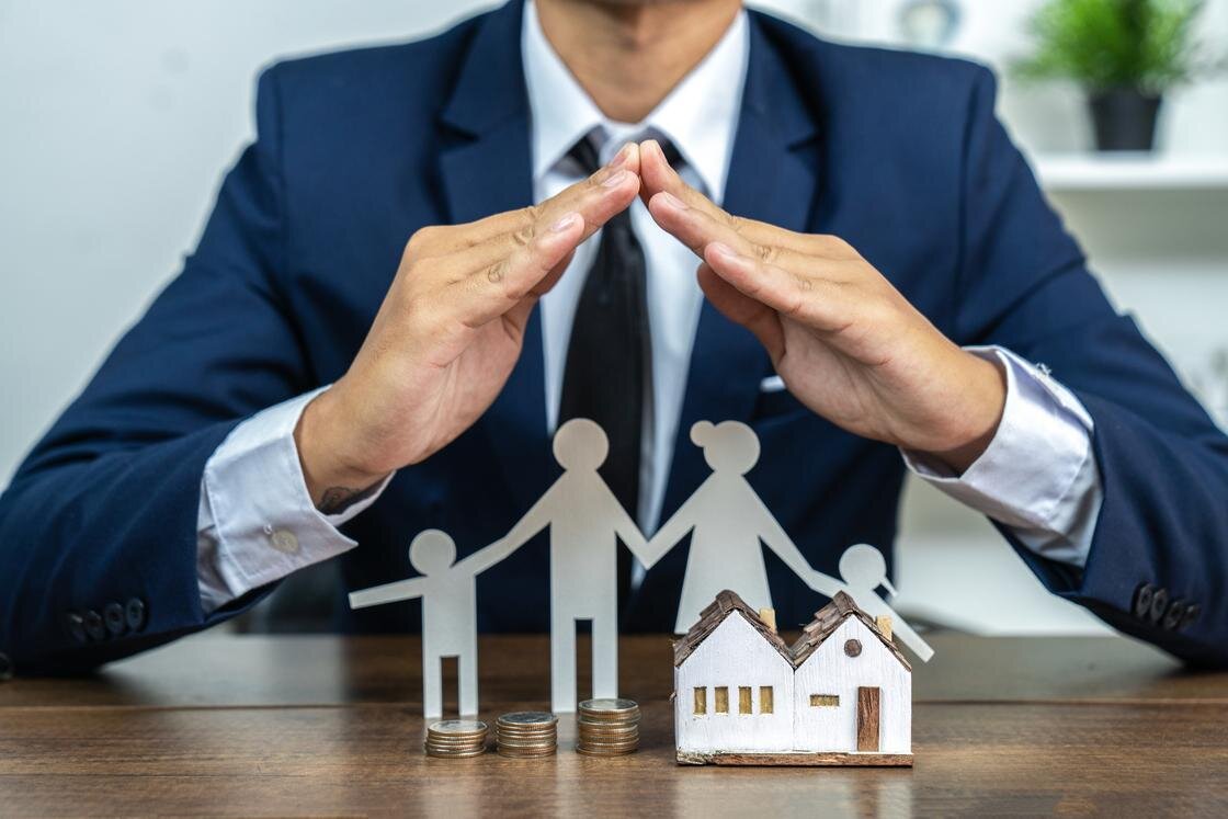    Мужчина закрывает руками человеческие фигурки и игрушечный домик:krisanapong detraphiphat/Getty Images