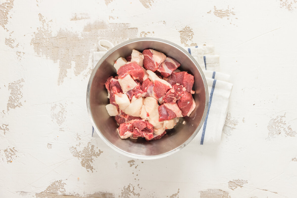 1. Подготовьте баранину. Вымойте ее и обсушите. Затем нарежьте небольшими кусочками и сложите в миску. Курдючный жир нарежьте маленькими кубиками. Добавьте в миску к баранине.